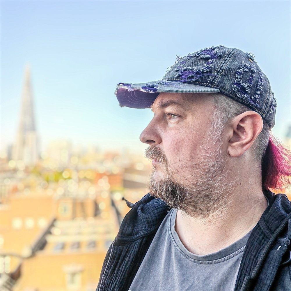 Rost in profile, looking out over the London skyline with the Shard in the distance